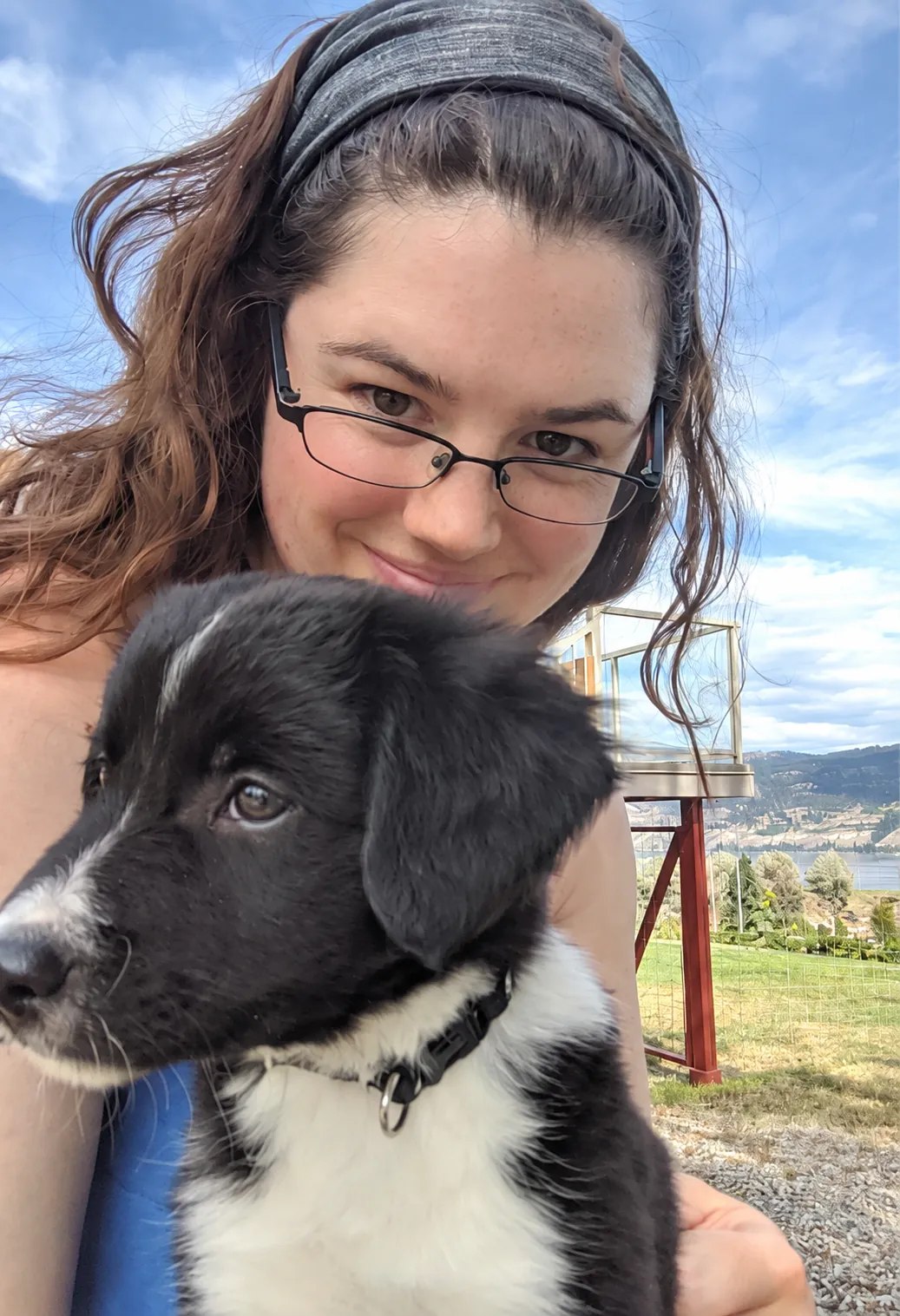 Caitlyn holding Daphne, her black and white dog, outdoors in the mountains